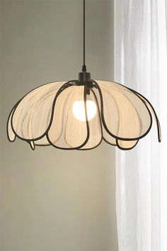 a light hanging from a ceiling in front of a window with white drapes on it