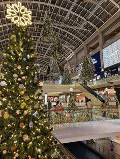 a christmas tree is in the middle of a shopping mall with lights and decorations on it