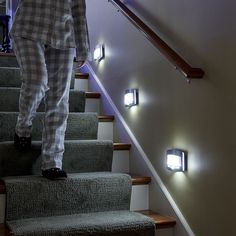 a person walking up some stairs with their feet on the handrail and lights above them