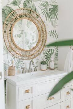 a bathroom with a mirror, sink and palm leaves on the wall