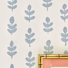 the wallpaper is decorated with blue leaves on white and pink walls, along with a gold frame