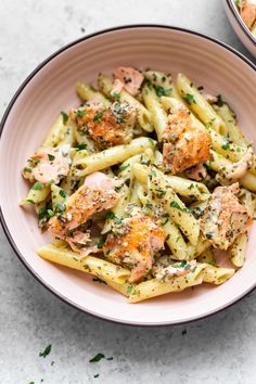 pasta with salmon and parsley in a pink bowl next to a pot of broccoli