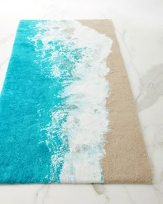 a rug with blue and white waves on the beach in front of a marble floor