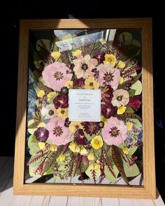 a wooden frame with flowers in it and a plaque on the front that says,