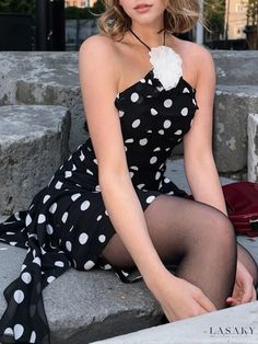 a woman is sitting on some steps wearing a polka dot dress