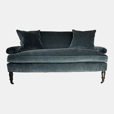 a blue couch with two pillows on it's back and one arm folded down