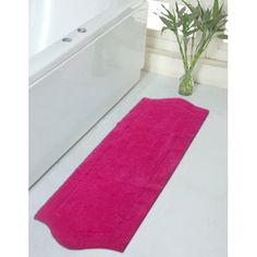 a pink bath mat sitting on top of a bathroom floor next to a white tub