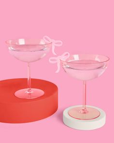 two empty wine glasses sitting next to each other on top of a pink tablecloth