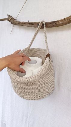 a person holding a basket with two rolls of toilet paper in it and a hand on the handle