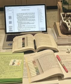 an open book sitting on top of a table next to a laptop computer and books