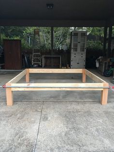 a wooden bed frame sitting in the middle of a garage with no mattresses on it