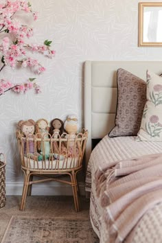 a bed with pink flowers on the wall next to a basket filled with toys and other items