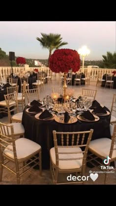 a table set up with black and white linens, gold chargers and red roses