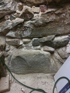 an old stone wall with wires attached to it and a box on the ground next to it