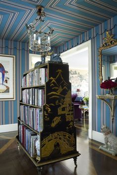 a bookshelf in the middle of a room with blue and white striped walls