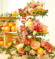 an arrangement of flowers and fruit on display