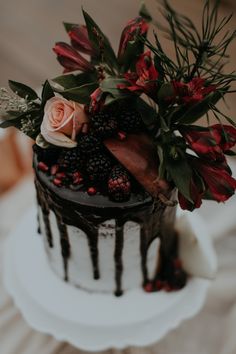 a close up of a cake with flowers on the top and chocolate icing drizzle