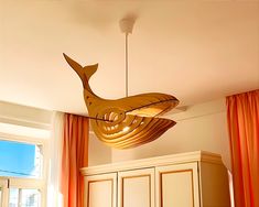 a light fixture hanging from the ceiling above a bed in a room with orange curtains