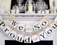 we are proud of you banner hanging on fireplace mantel with chandelier in background