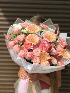 a woman holding a bouquet of pink and white flowers