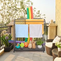 a rack with towels and toys on top of a patio next to potted plants