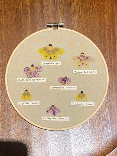 a cross stitch project with flowers and words written on the back of it, sitting on a wooden surface