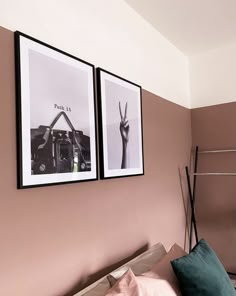 two framed pictures hang on the wall above a bed with pink sheets and pillows,