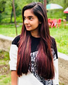 a girl with long hair standing in the park