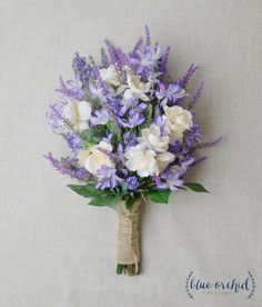 purple and white flowers are tied to a burlocked bridally bouquet