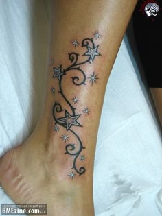 a tattoo on the foot of a person with stars and swirls around it,