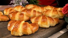 many croissants are lined up on a cutting board with flowers in the background