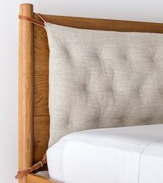 a close up of a bed with a wooden headboard and white linens on it