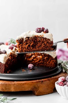 someone is holding a piece of cake with white frosting and cranberries on top