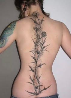 the back of a woman's body with tattoos on her stomach and flowers growing out of it