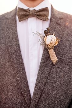 a man in a suit and bow tie with a boutonniere on his lapel