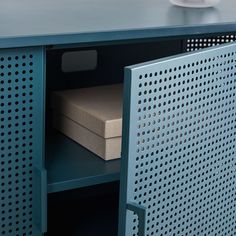 a close up of a metal cabinet with a box on the bottom and a cup in front