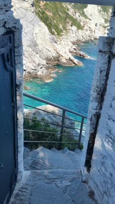 an open door leading to the ocean from a stone building with stairs going up it