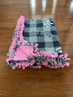 a new york blanket with pink ruffles on it sitting on a wooden floor