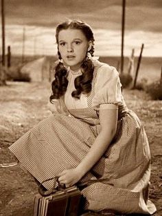 an old photo of a woman sitting on the ground with a suitcase in her hand