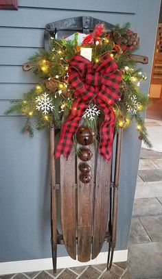 a wooden sled with christmas decorations and lights on the side of a house in front of a door