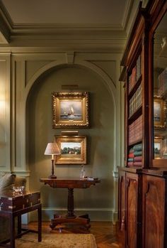 a living room filled with lots of furniture and paintings on the wall next to bookshelves