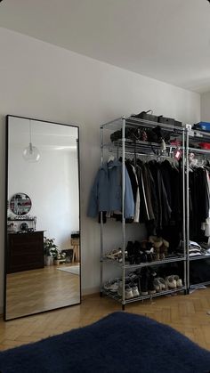 a closet with clothes and shoes in it next to a large mirror on the wall