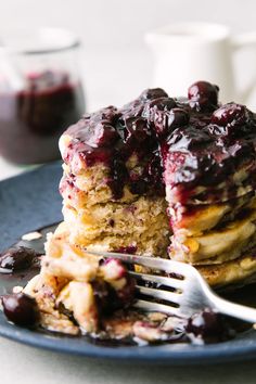 a blue plate topped with pancakes covered in blueberry compote sauce and syrup