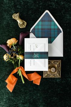 the wedding stationery is laid out on green velvet