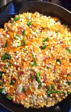 a skillet filled with corn and vegetables on top of a stove