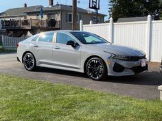 a silver car parked in front of a white fence