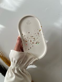 a person holding a white plate with brown sprinkles on it and their left hand