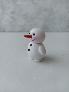 a small white snowman with red nose and black dots on it's body