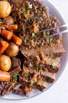 a white plate topped with meat, potatoes and carrots