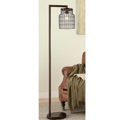 a floor lamp with a birdcage shade on it's side and a brown chair in the background